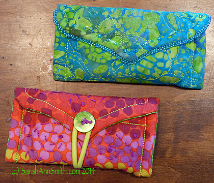 Here are two of my cardholders.  These are so fast--they would make a great gift-card "wrapping" for Christmas, then the recipient can continue to use the holder.  They are sized to fit business cards, but I use the green one for all those extra (annoying!) store cards for the grocery, discount stores, pharmacy, and so on.  The green was the original; despite being beaded on the flap and used heavily for three years, it is still in great condition.  The warm-tones bag is new.  The project in the magazine uses a snap closure, but I really like this one which uses a heavy duty hair elastic and button.