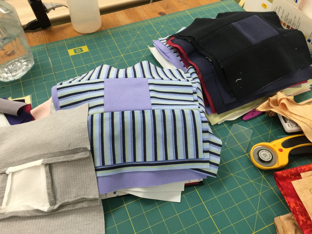 I've been piecing some blocks (who me?): made of turtleneck shirts. Eek! I had to stabilize all of them with interfacing (gray one in lower left corner). As expected, the machine breezed through without nary a burp. 