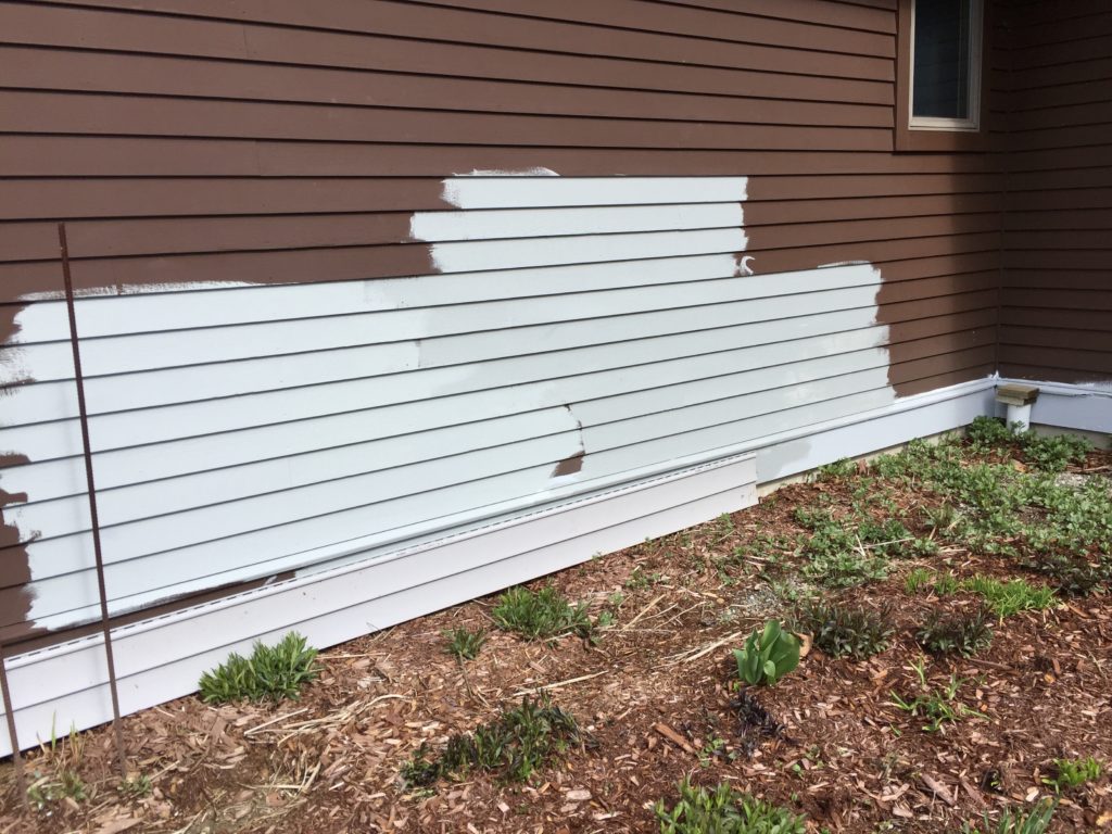 The house is brown.  Dark brown.  That may be fine on some houses in the right setting, but on a ranch house in the middle of a big open space it looks like a dark  hulk.  So we decided on a medium-light gray with white trim when we built the garage.  Now it is time to do the house, which has "solid stain" on it (the dark brown).  The stain holds up a LOT better than paint, but along the bottom was peeling, so it was time.  In this image, I'm testing various mixes to see what best matches the siding on the garage (resting on the ground).  The answer was none of these!