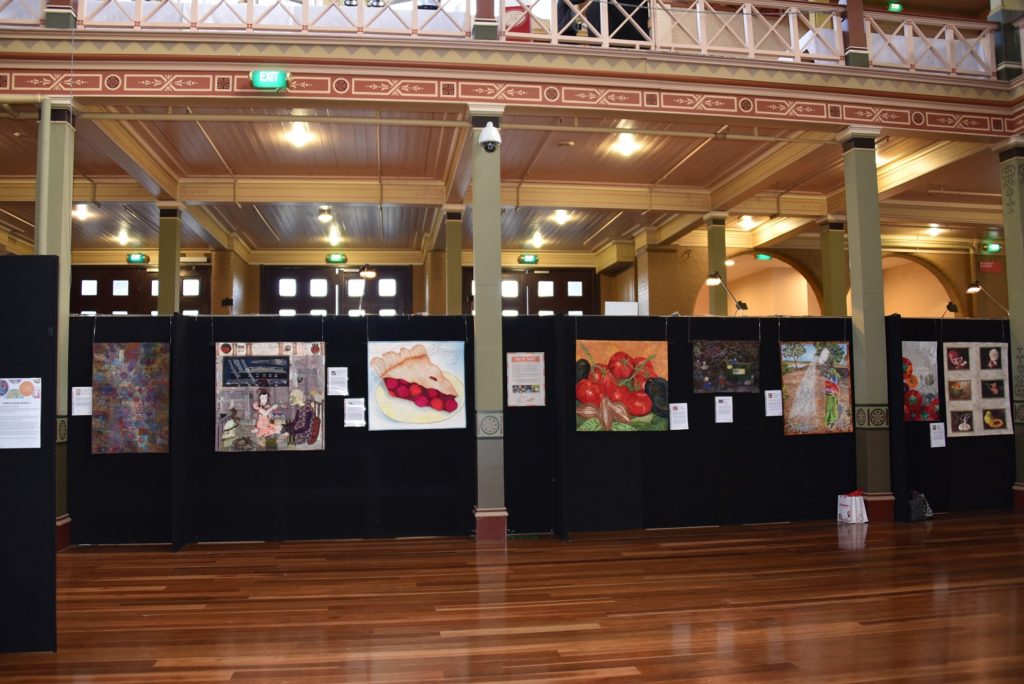 My "tomatoes" quilt, Insalata, on display at the AQC.  LOVE that it is facing the center in a prime spot, and love the black walls on which the works are displayed.  